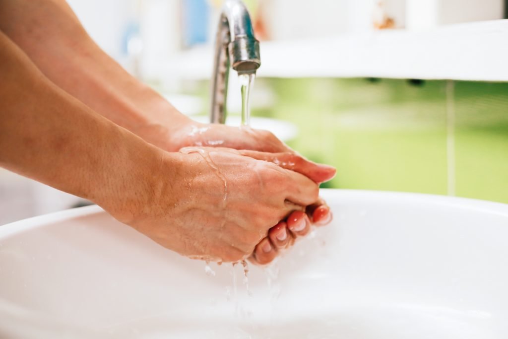 Close-up of human hands washing away germs and bacteria under the sanitary crane.
